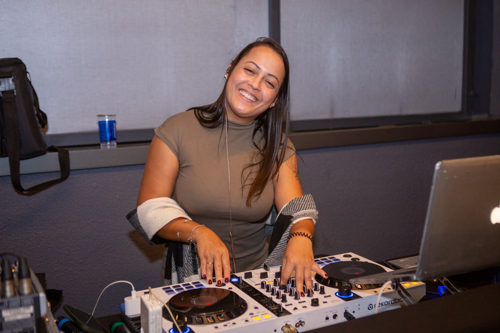 DJ Thaa sorrindo enquanto toca na controladora