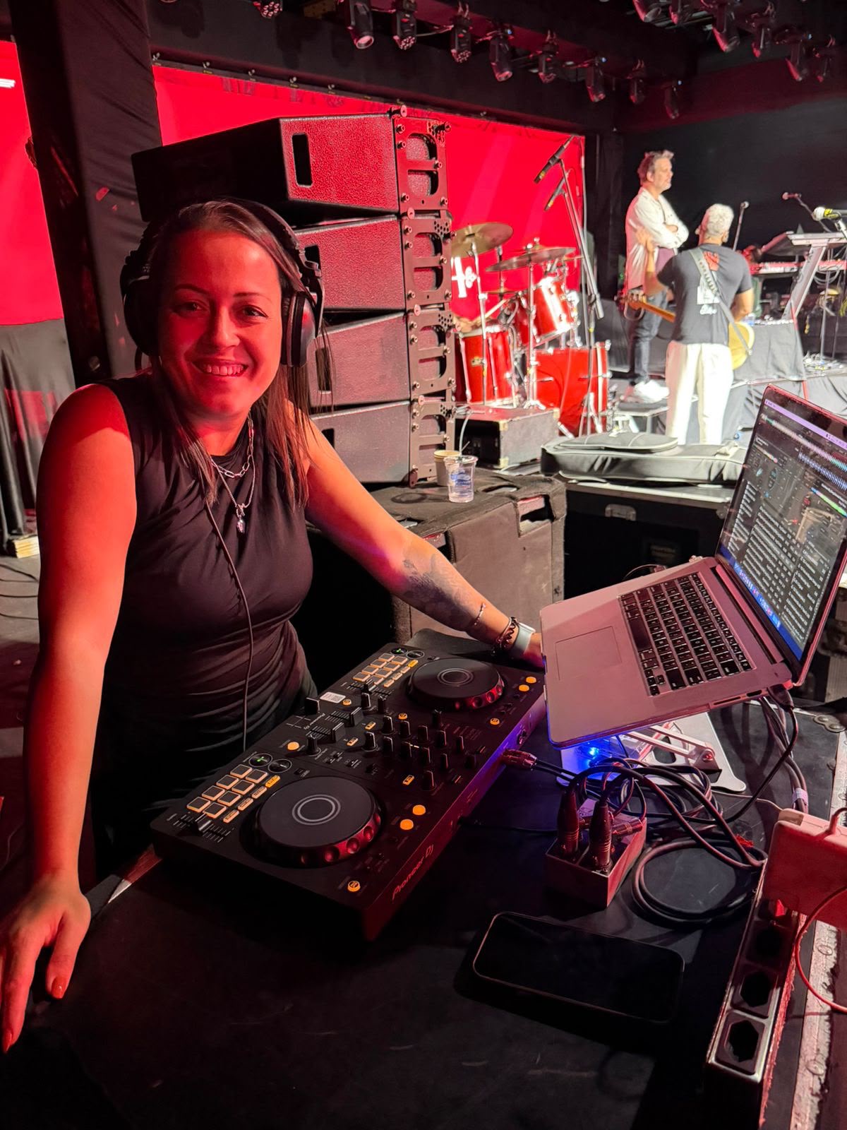 DJ Thaa tocando ao lado do palco com músicos ao fundo